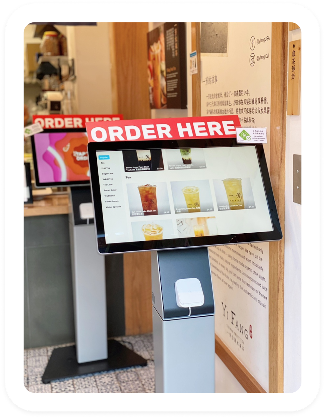 Two self-service ordering kiosks at a tea shop, with drink menus, payment terminals and āOrder Hereā signs.